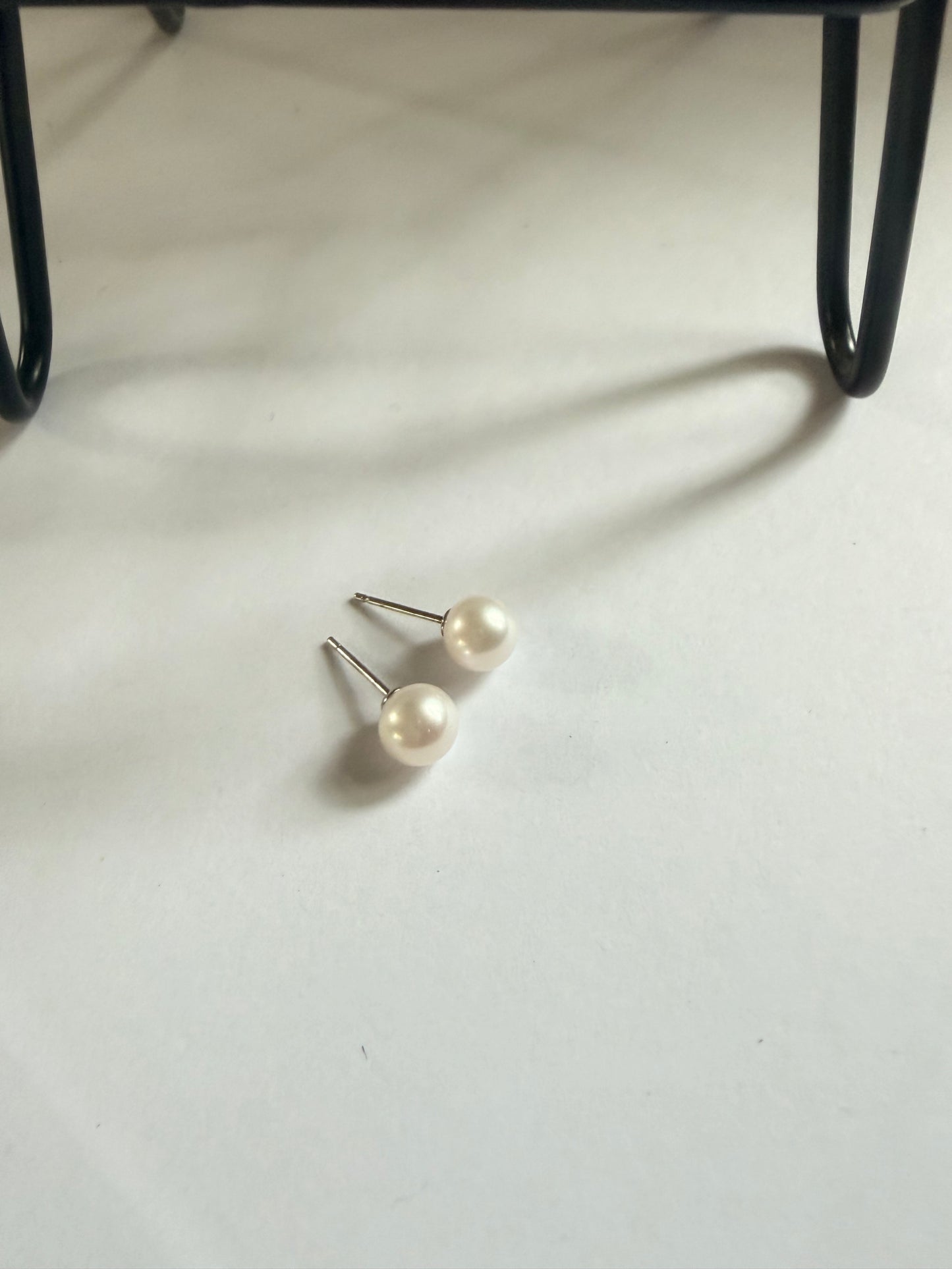 Pair of 7mm natural freshwater pearl stud earrings with sterling silver posts on a white surface.