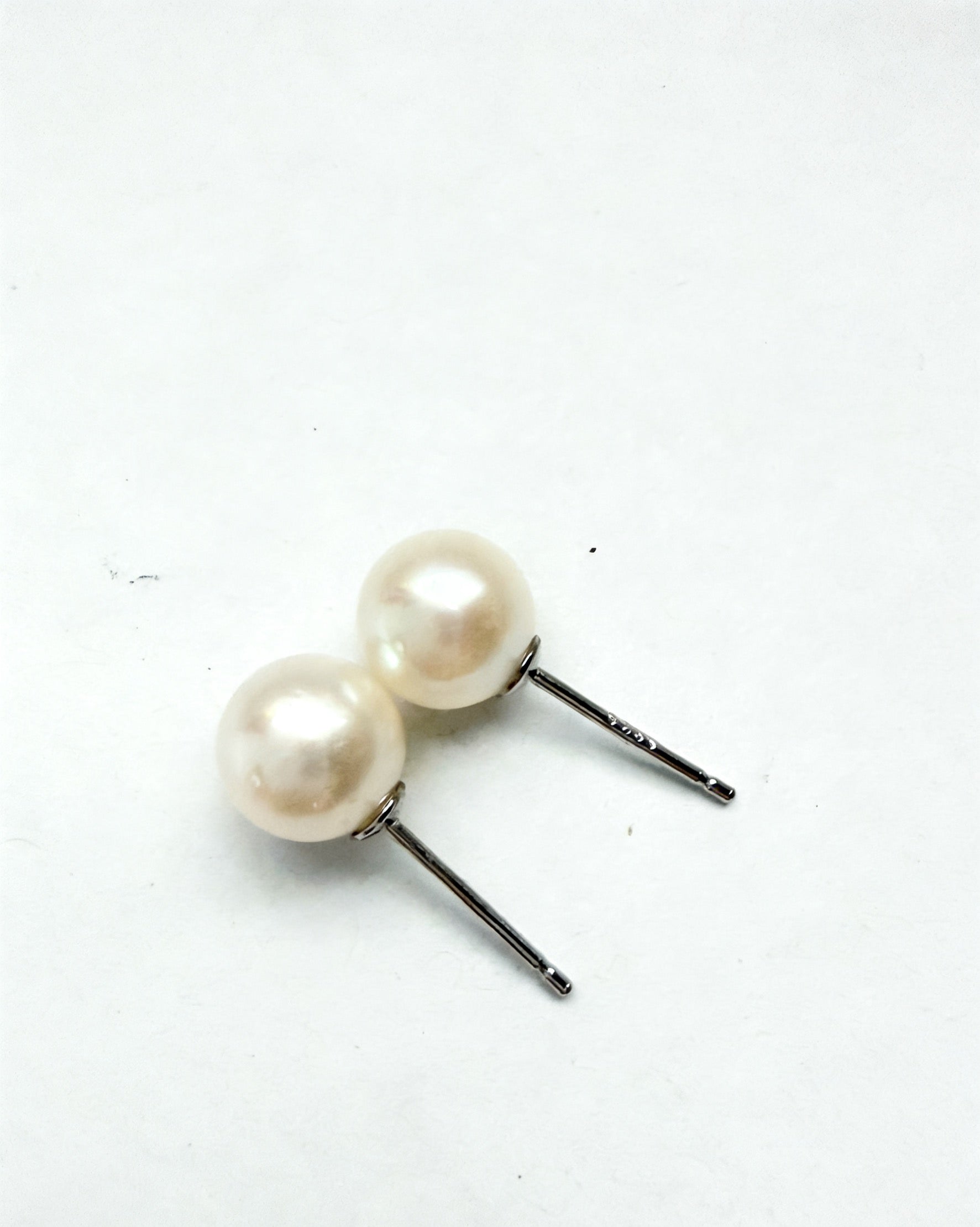 Two 7mm white freshwater pearl stud earrings with sterling silver posts on a white background.