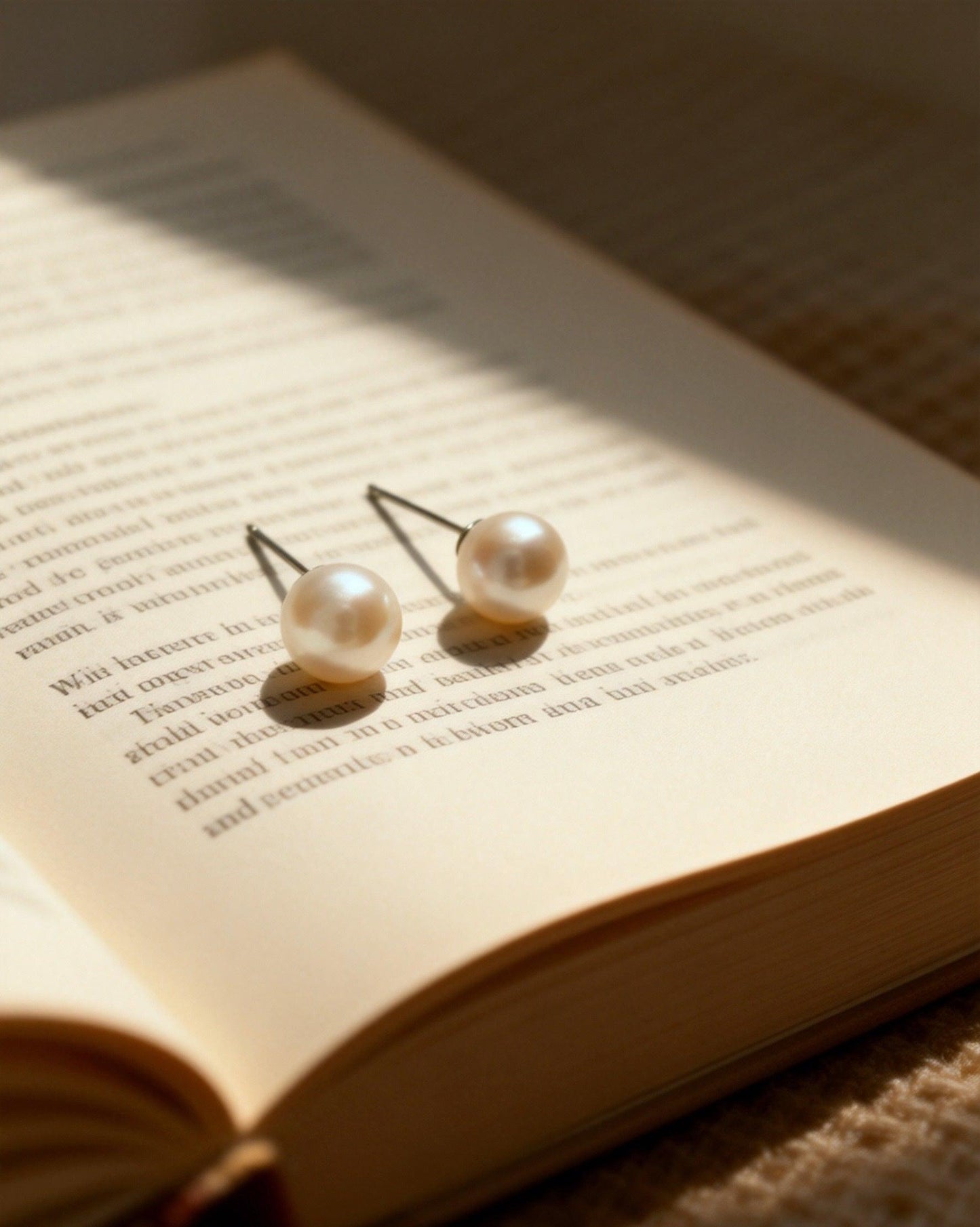 Pair of Luvymia 7mm South Sea pearl stud earrings with natural luster on an open book.