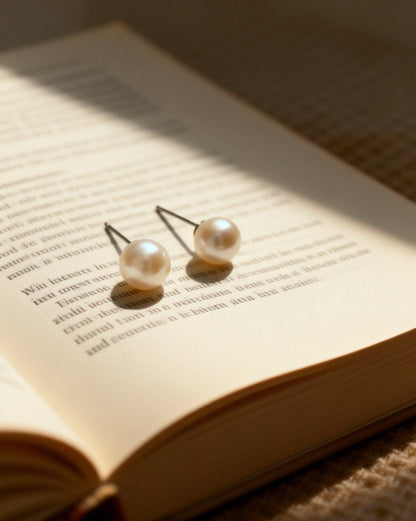 Pair of Luvymia 7mm South Sea pearl stud earrings with natural luster on an open book.