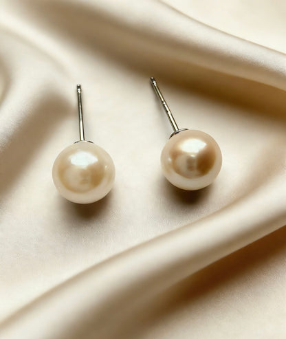 Pair of 6-7mm natural saltwater pearl stud earrings with soft luster and 925 sterling silver posts on satin.