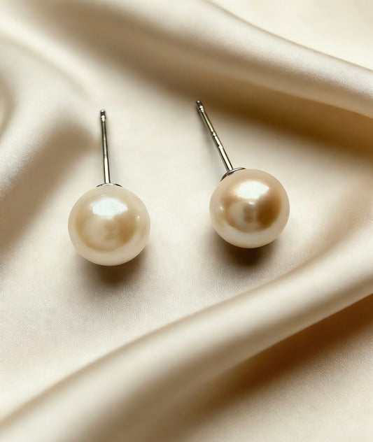 Pair of 6-7mm natural saltwater pearl stud earrings with soft luster and 925 sterling silver posts on satin.