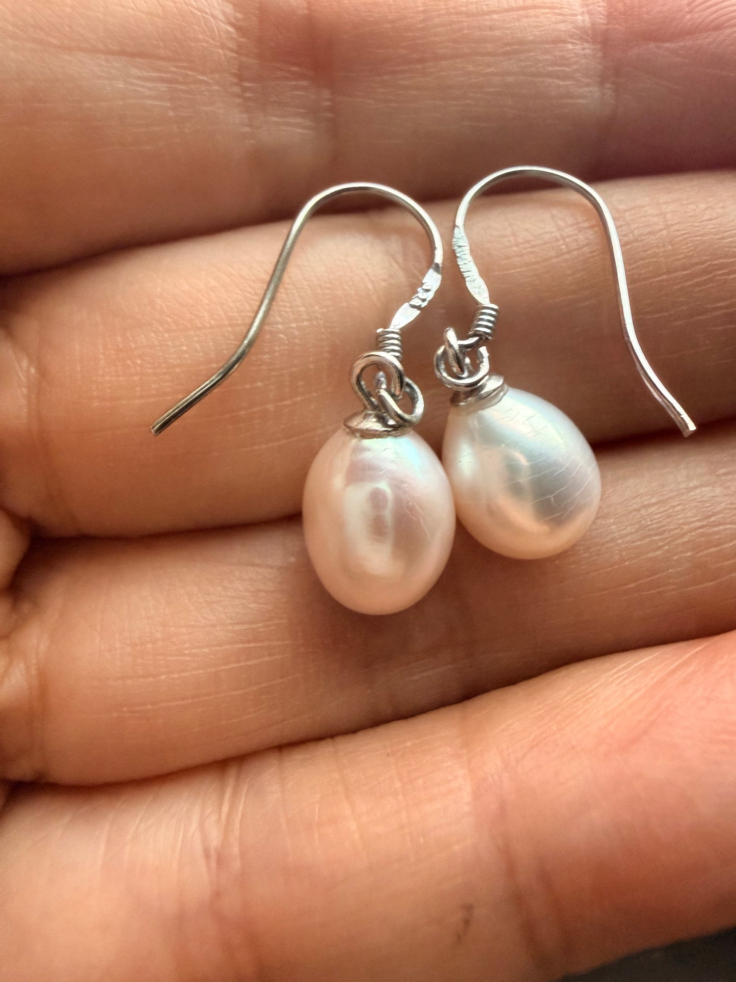 Baroque freshwater pearl drop earrings with 925 sterling silver hooks, held in a hand.