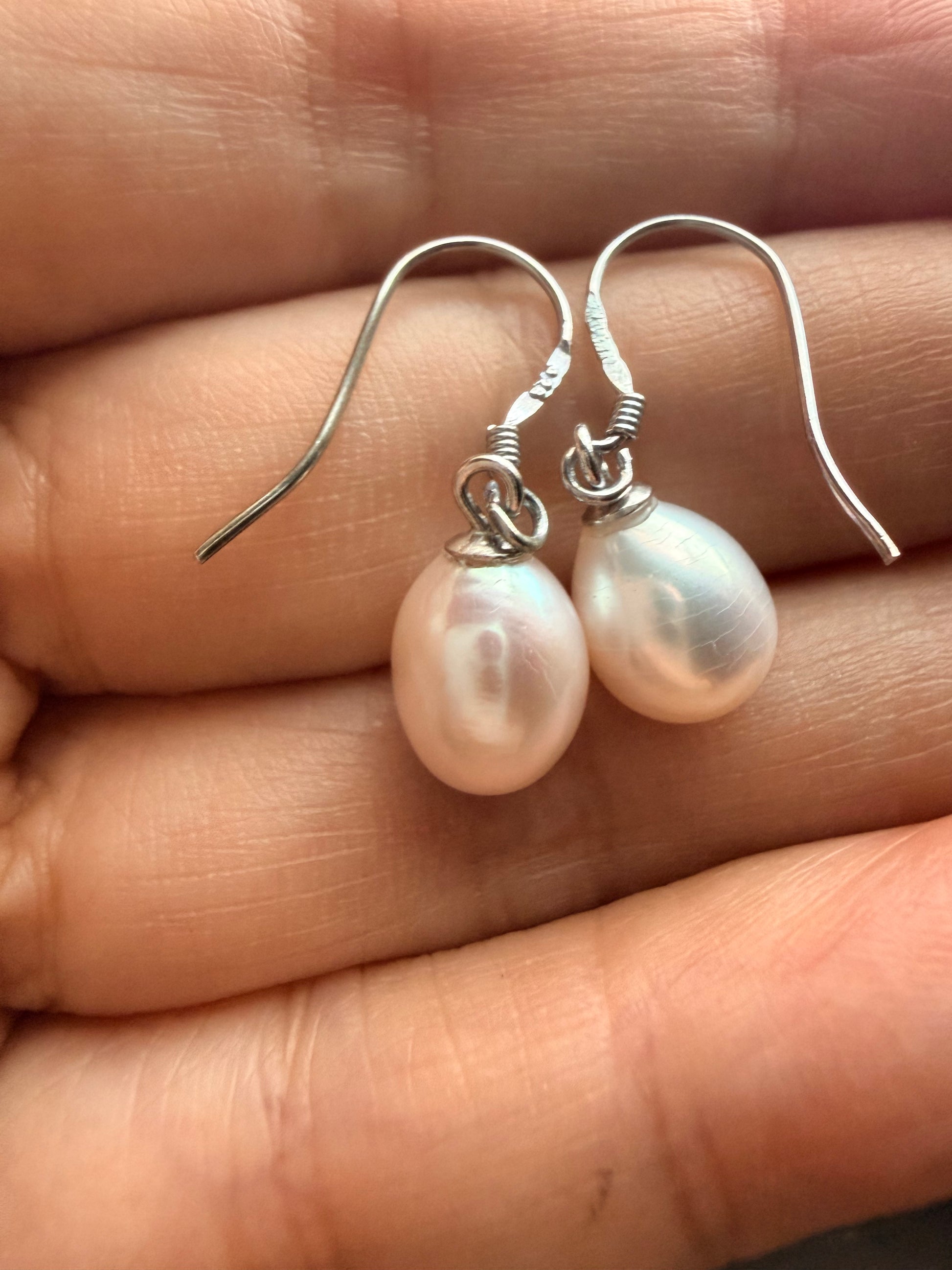Baroque freshwater pearl drop earrings with 925 sterling silver hooks, held in a hand.