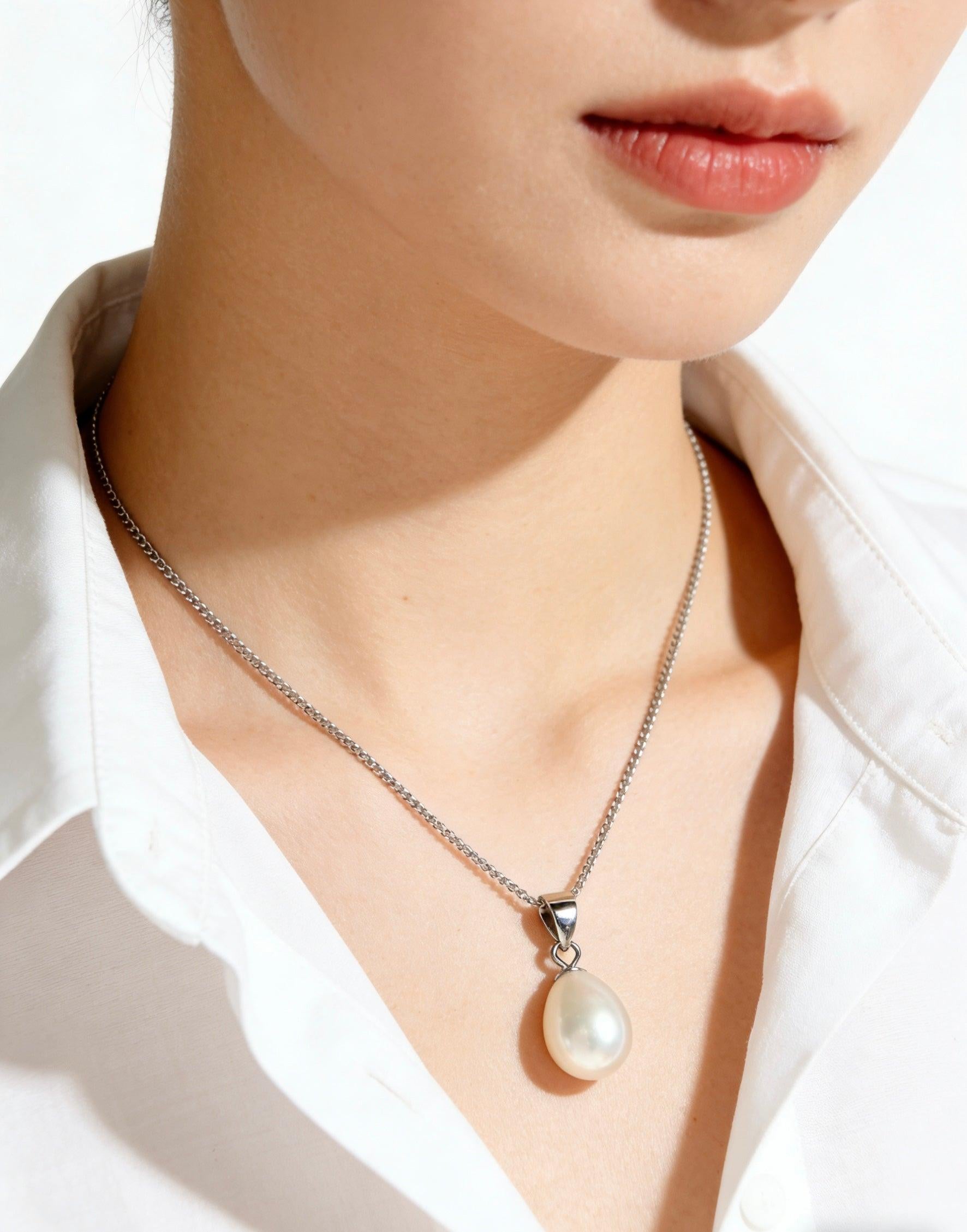 Woman wearing a minimalist 925 sterling silver necklace with a cream-white baroque freshwater pearl pendant.