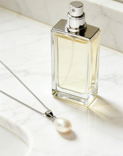 Baroque freshwater pearl pendant necklace with a 925 sterling silver chain next to a perfume bottle on marble.