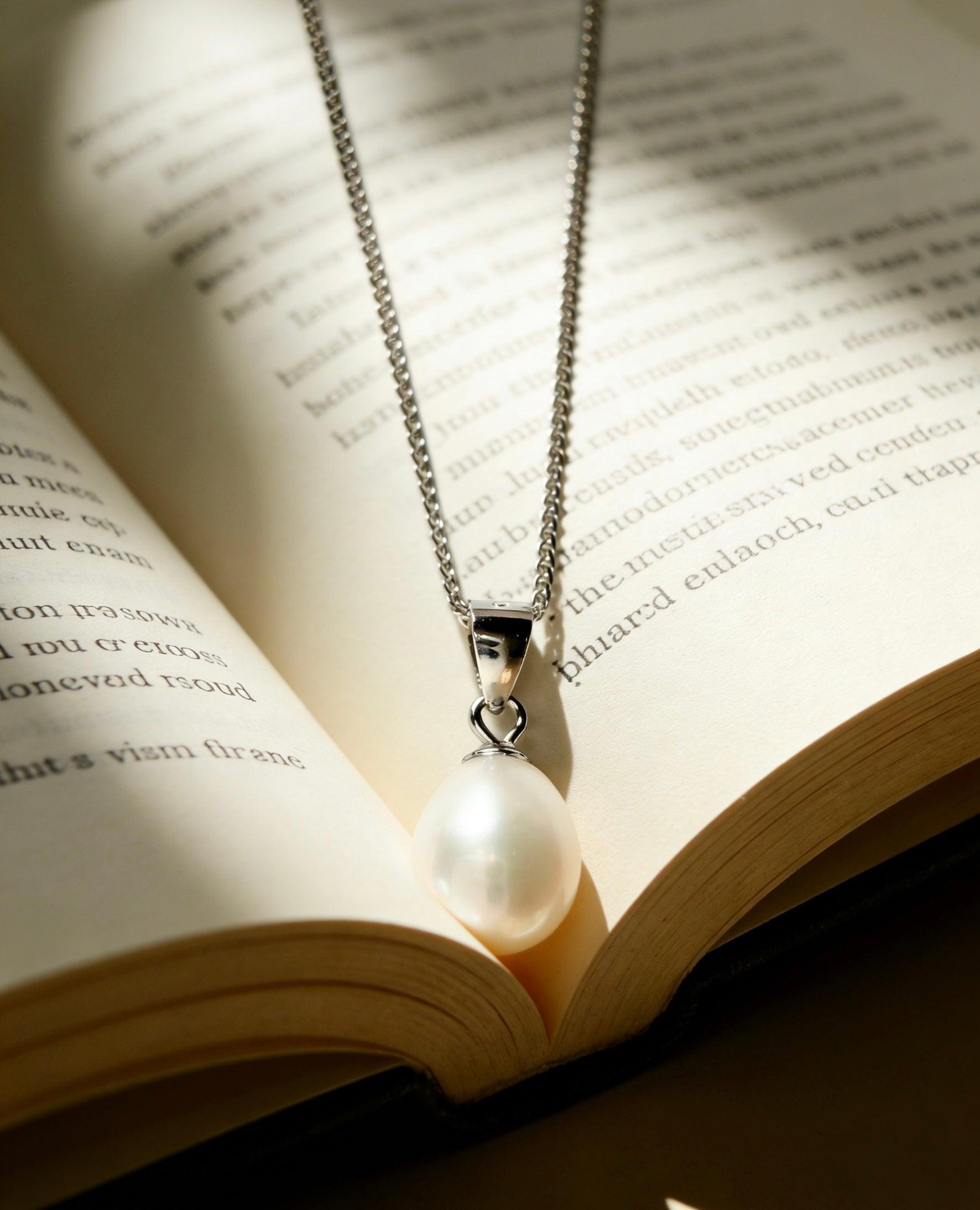 Luvymia baroque freshwater pearl pendant necklace with a 925 sterling silver chain on an open book.