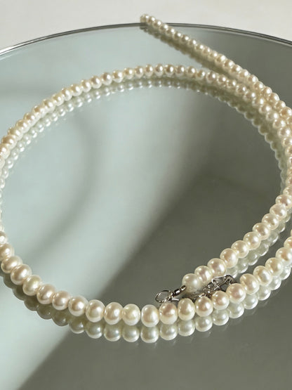 Luvymia 3-4mm near-round freshwater pearl necklace with 925 sterling silver clasp on a mirror.
