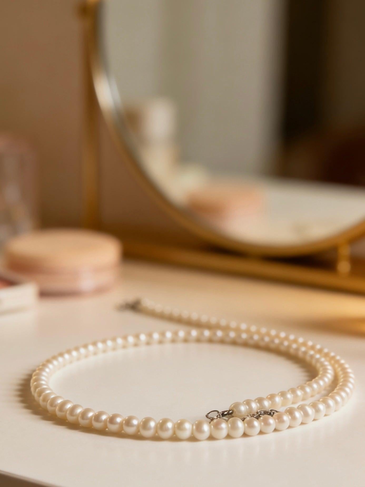 Delicate 3-4mm near-round freshwater pearl necklace with a 925 sterling silver clasp on a vanity.