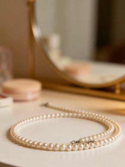 Delicate 3-4mm near-round freshwater pearl necklace with a 925 sterling silver clasp on a vanity.