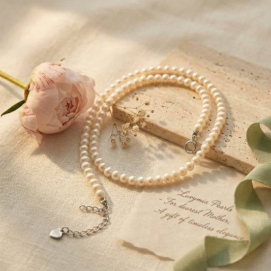 Delicate 3-4mm near-round freshwater pearl necklace with 925 sterling silver clasp, beside a pink peony.